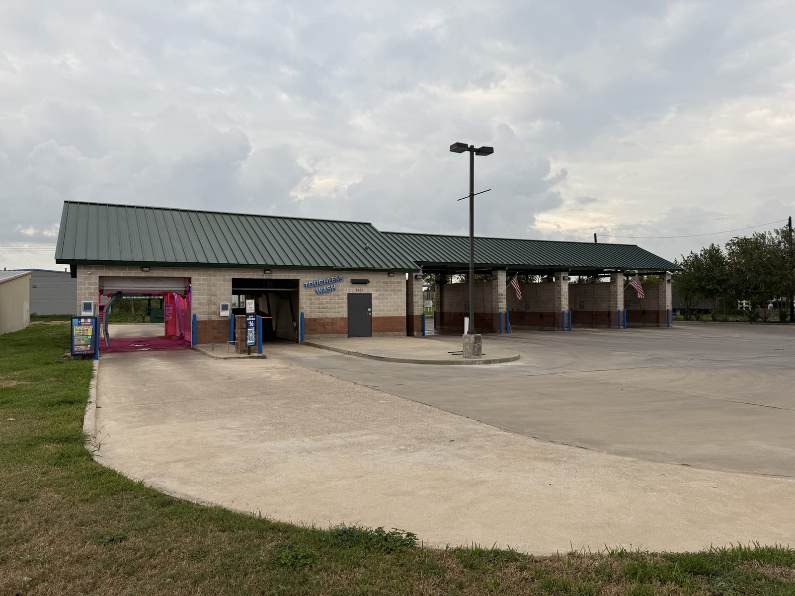 Gilbert's Car Wash in Victoria, TX — tan brick building with a green metal roof, self-serve wash bays, and covered vacuum stations.